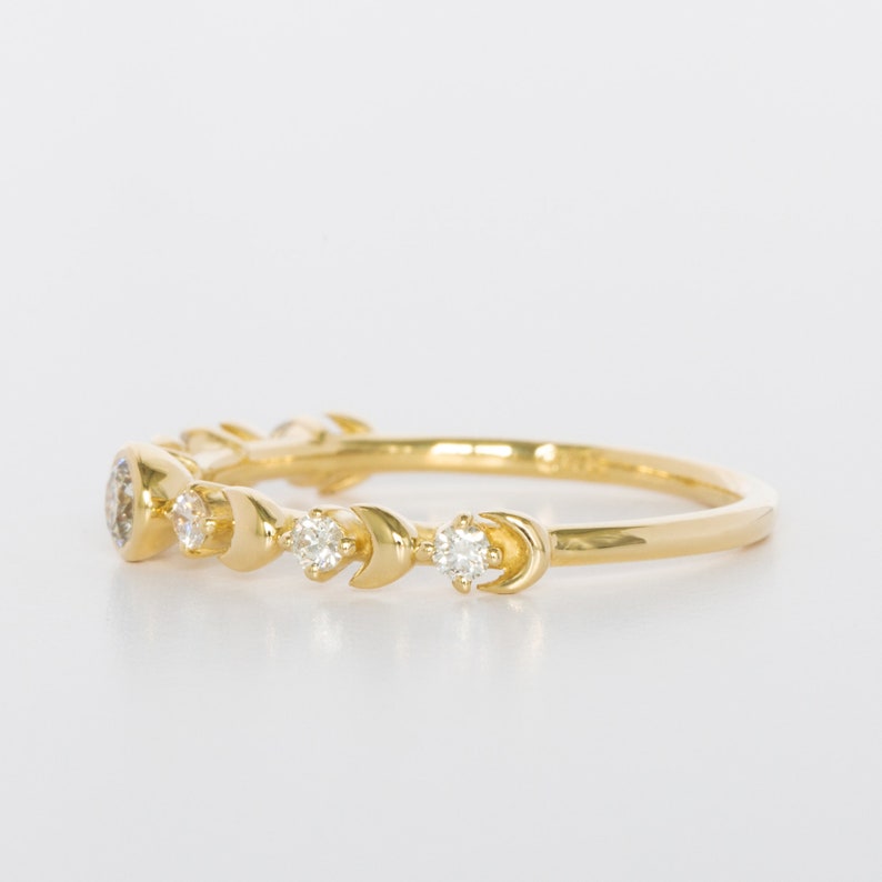 K&ouml;nnte beinhalten: Ein Goldring mit einem Halbmond-Design und kleinen Diamanten, die in die Band eingefasst sind.