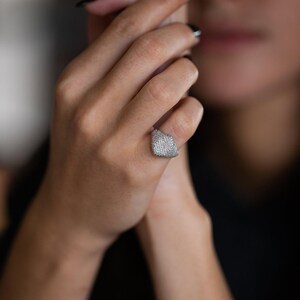 closeup of a woman wearing a solid gold signet ring with diamonds