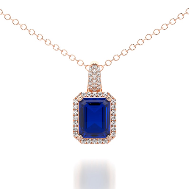 This is a classic and elegant 14K solid gold Emerald cut blue Sapphire pendant, set with a sparkling halo of white diamonds, the perfect anniversary or bridal necklace.