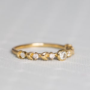 K&ouml;nnte beinhalten: Ein zarter Goldring mit einem Halbmond-Design und kleinen Diamanten. Der Ring hat einen gr&ouml;&szlig;eren runden Diamanten in der Mitte.