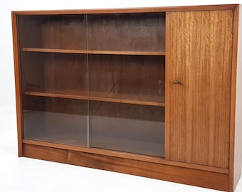 May include: A mid-century modern wooden display cabinet with glass sliding doors and a solid door on the right. The cabinet has three shelves and a warm, natural wood finish. The cabinet is designed for storage and display.