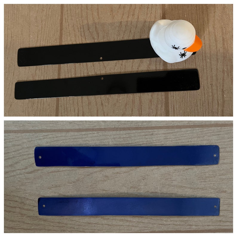Puede incluir: Dos tiras de metal negro y dos tiras de metal azul. Las tiras son planas y rectangulares con bordes redondeados. Cada tira tiene un peque&ntilde;o agujero en el centro.