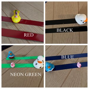 Puede incluir: Cuatro tiras magn&eacute;ticas de diferentes colores con patitos de goma sobre ellas. Las tiras est&aacute;n etiquetadas como "ROJO", "NEGRO", "VERDE NE&Oacute;N" y "AZUL".
