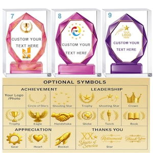 May include: Three crystal awards with pink, purple, and violet accents. Each trophy has a unique shape and base, with space for custom text and logos. A chart below displays optional achievement and leadership symbols.
