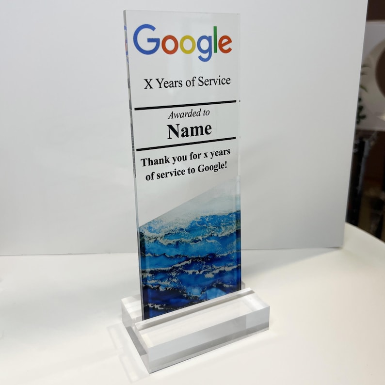 Puede incluir: Una placa de premio de acr&iacute;lico transparente con el logotipo de Google y el texto "X Years of Service" y "Awarded to Name". La placa tambi&eacute;n incluye el texto "Thank you for x years of service to Google!" y un dise&ntilde;o abstracto azul y blanco.