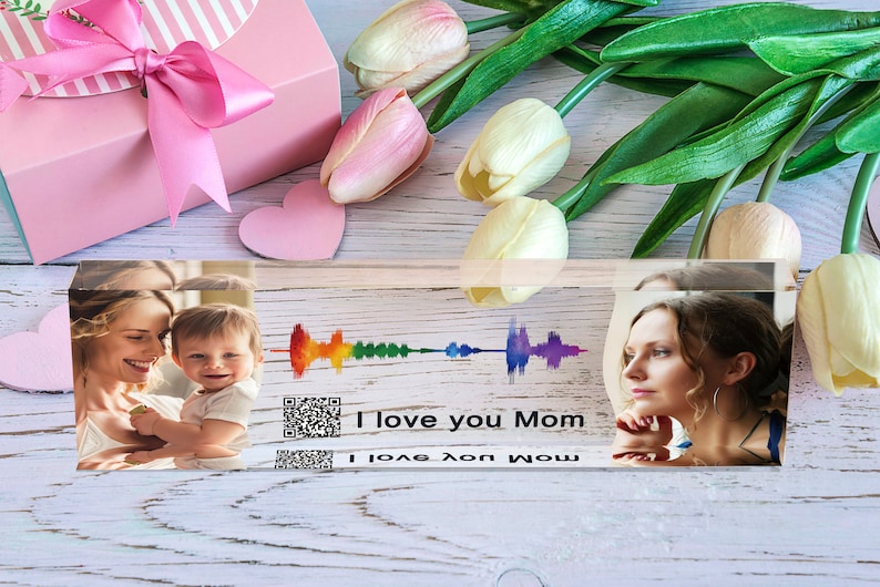Pu&ograve; includere: Un blocco di acrilico trasparente con due foto di una madre e un bambino, e una donna. Il blocco presenta anche un'onda sonora arcobaleno, un codice QR e il testo "I love you Mom".