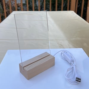 以下が含まれることがあります： 木製のベースと白いUSBケーブルで照らされた透明なアクリルサイン。木製のベースには、アクリルサインを保持するための2つのスロットがあります。USBケーブルにはオン/オフスイッチが付いています。