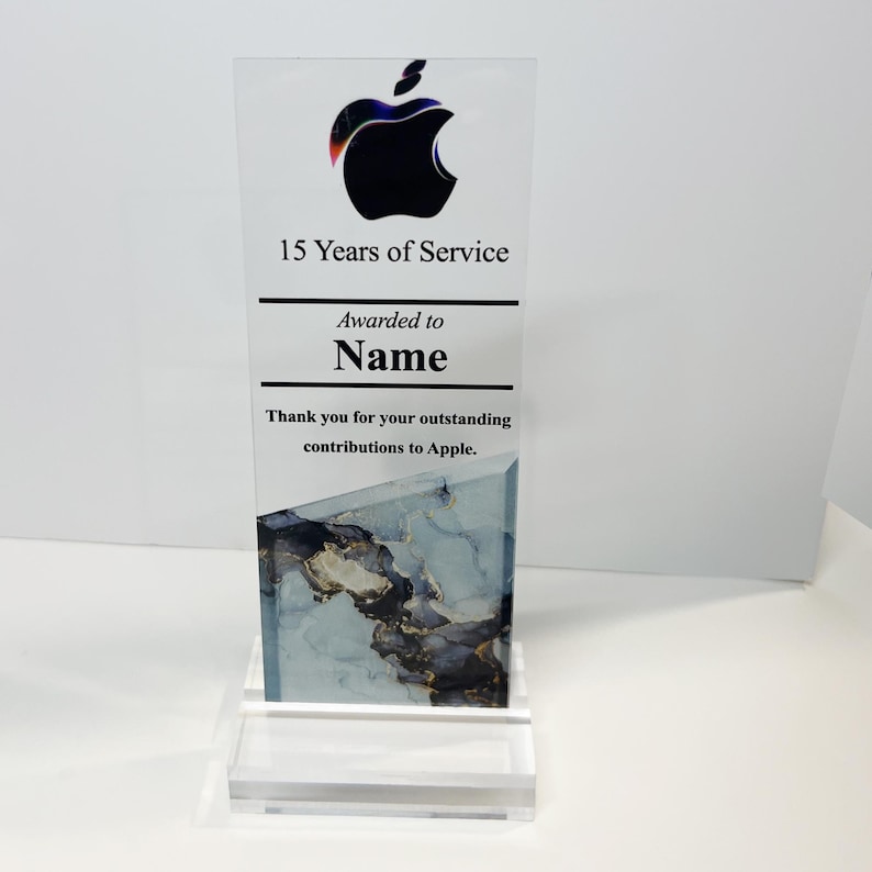 Puede incluir: Una placa de premio de acr&iacute;lico transparente con un logotipo de Apple negro y el texto "15 Years of Service". La placa tambi&eacute;n incluye el texto "Awarded to Name" y "Thank you for your outstanding contributions to Apple."