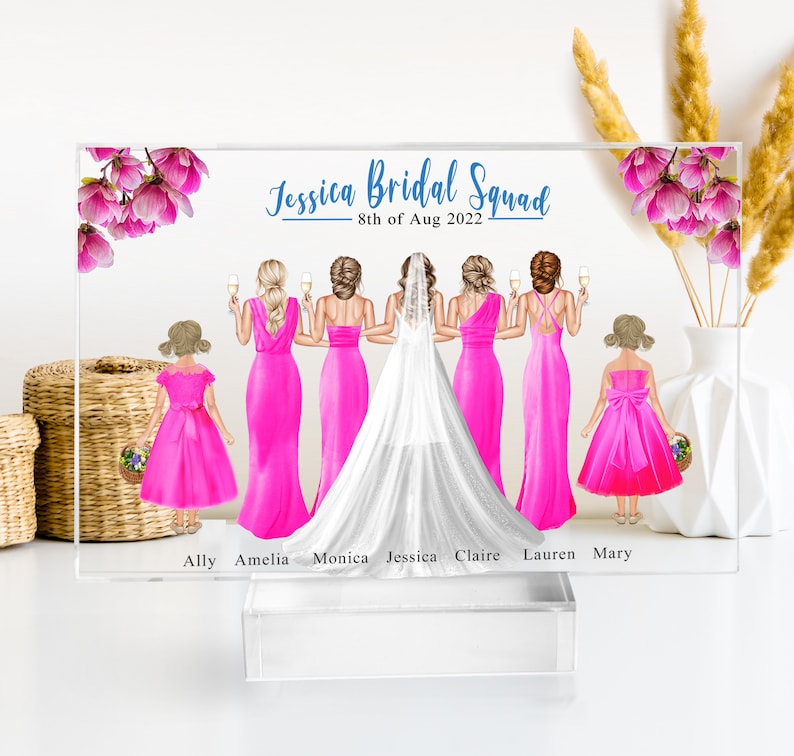 May include: A personalized acrylic plaque with a bridal squad illustration. The bride is in a white gown and the bridesmaids are in pink dresses. The text reads "Jessica Bridal Squad 8th of Aug 2022" and lists the names of the bridal party members: Ally, Amelia, Monica, Jessica, Claire, Lauren, and Mary.
