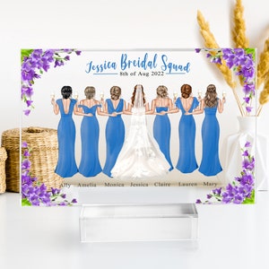 May include: A clear acrylic plaque with a floral design and a group of women in blue dresses and a bride in a white dress. The text "Jessica Bridal Squad - 8th of Aug 2022" is at the top of the plaque. The names of the women are listed below the image: Ally, Amelia, Monica, Jessica, Claire, Lauren, Mary.