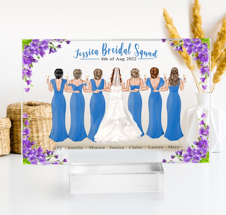 May include: A clear acrylic plaque with a floral design and a group of women in blue dresses and a bride in a white dress. The text "Jessica Bridal Squad - 8th of Aug 2022" is at the top of the plaque. The names of the women are listed below the image: Ally, Amelia, Monica, Jessica, Claire, Lauren, Mary.