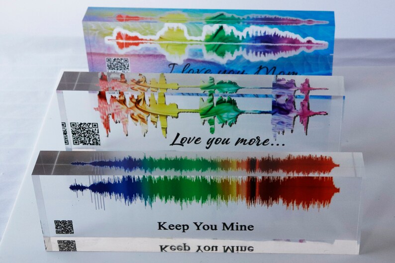 Pu&ograve; includere: Tre blocchi di acrilico trasparenti con motivi di onde sonore colorati e testo. Il blocco superiore dice "I love you Mom". Il blocco centrale dice "Love you more..." Il blocco inferiore dice "Keep You Mine" e "Keeb JOM WIDG".