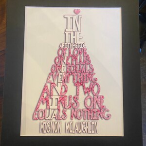 May include: A framed print with a pink and white design that reads "In the arithmetic of love, one plus one equals everything and two minus one equals nothing." The print is signed "Mignon McLaughlin".