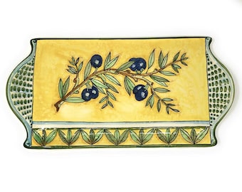 May include: A rectangular ceramic serving tray with a yellow background and a green olive branch design. The tray has a green and white border with a scalloped edge.
