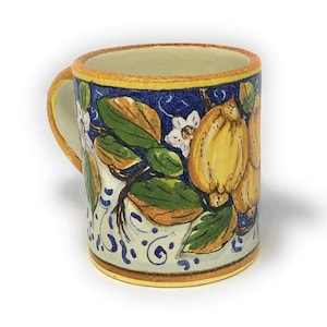 May include: A ceramic mug with a blue and white floral design featuring lemons and leaves. The mug has a yellow rim and handle.