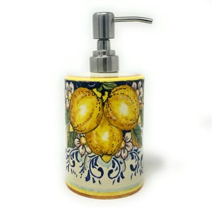 Könnte beinhalten: Keramik-Seifenspender mit einer Pumpe aus Edelstahl. Der Spender hat ein farbenfrohes Design mit Zitronen und Blumen auf blau-weißem Hintergrund.