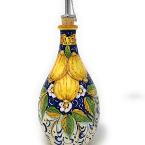 May include: Ceramic olive oil bottle with a blue and white floral design featuring lemons. The bottle has a cork stopper and a stainless steel pour spout with a chain.