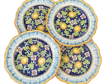 May include: Set of four blue and white ceramic dinner plates with a lemon and floral design. The plates have a scalloped edge and a yellow rim.