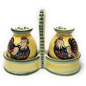 以下が含まれることがあります： 鶏のデザインと蓋に「Sale」と「Pepe」と書かれたセラミック製の塩とコショウ入れ。塩入れは、ハンドルが付いた黄色と緑色のホルダーに入っています。