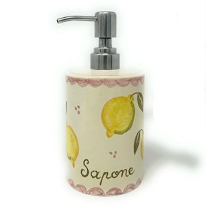 May include: A cream-coloured ceramic soap dispenser with a stainless steel pump. It features hand-painted yellow lemons and green leaves. The word "Sapone" is written in brown script. A pink scalloped border trims the top.