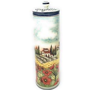 May include: Tall ceramic spaghetti jar with a lid. The jar is cylindrical and features a hand-painted Italian countryside scene with red poppies, a farmhouse, and cypress trees. The lid is white with blue accents and the word "Spaghetti".