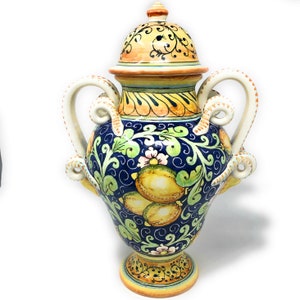 Könnte beinhalten: Eine Keramikvase mit Deckel, verziert mit einem blauen und gelben Blumendesign mit Zitronen. Die Vase hat zwei Henkel und einen runden Boden.