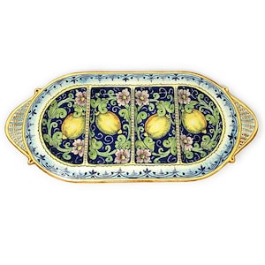 May include: A ceramic serving dish with four divided sections, featuring a hand-painted design of lemons and flowers on a blue background. The dish has a gold rim and handles.