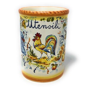 Może przedstawiać: Biały ceramiczny pojemnik na sztućce z wzorem koguta i napisem "Utensilli" w niebieskich literach. Kogut jest żółty, czerwony i niebieski z żółtym, czerwonym i zielonym ogonem.