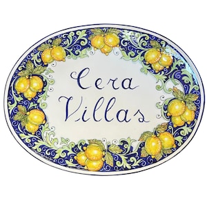 May include: An oval ceramic platter with a white center featuring the hand-painted blue text Cera Villas. The border is decorated with a dark blue background, green swirling foliage, and clusters of yellow lemons with green leaves.