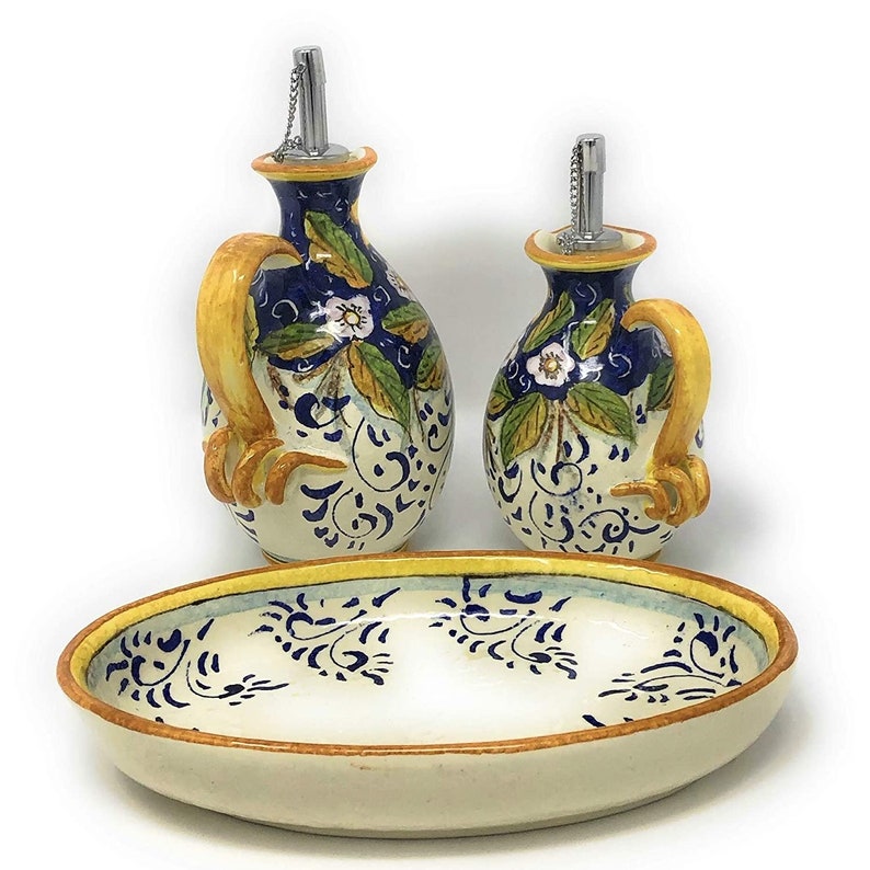 May include: A set of two ceramic oil and vinegar bottles with blue and yellow floral designs, sitting on a matching oval serving dish.