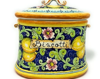 May include: A ceramic cookie jar with a yellow, blue, and green floral design. The jar has a lid with a handle and says "Biscotti" on the front.