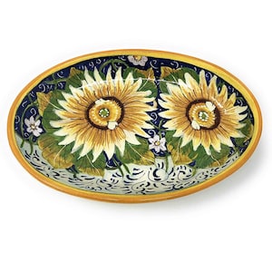 May include: An oval ceramic serving dish with a blue and white background. The dish is decorated with two yellow sunflowers and green leaves. The rim of the dish is a bright yellow.