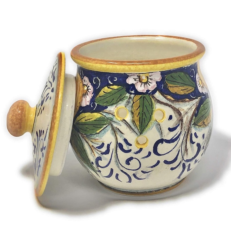 Peut inclure: Un pot en c&eacute;ramique blanche avec un couvercle, d&eacute;cor&eacute; de motifs floraux bleus et jaunes. Le pot a une forme ronde et un petit bouton sur le couvercle.