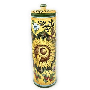 Op de afbeelding: Een gele keramische pot met een groen deksel en een zonnebloemdessin. De pot is versierd met een zonnebloem, bessen en andere bloemen. Het deksel heeft het woord "Spaghetti" erop.
