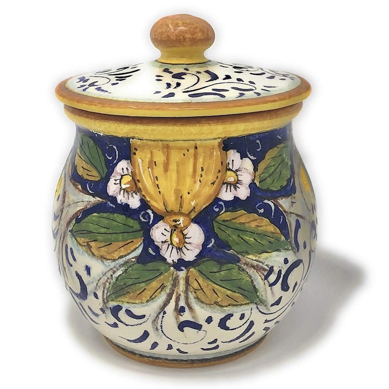 Peut inclure: Un petit pot en c&eacute;ramique avec un couvercle, d&eacute;cor&eacute; d'un motif floral dans des tons de jaune, vert, blanc et bleu. Le pot a un corps rond et un bord l&eacute;g&egrave;rement &eacute;vas&eacute;.