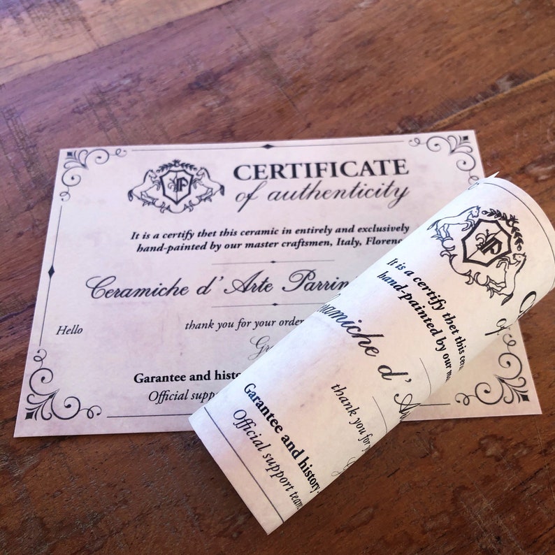 May include: A certificate of authenticity and a rolled-up paper with text. The certificate has decorative borders and the words "CERTIFICATE of authenticity". The rolled paper says "Ceramiche d'Arte Parrini" and "hand-painted".