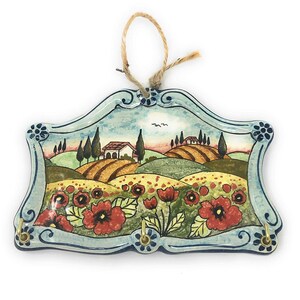 May include: Ceramic key holder with a painted scene of a Tuscan landscape with rolling hills, a farmhouse, and red poppies. The key holder has three hooks.