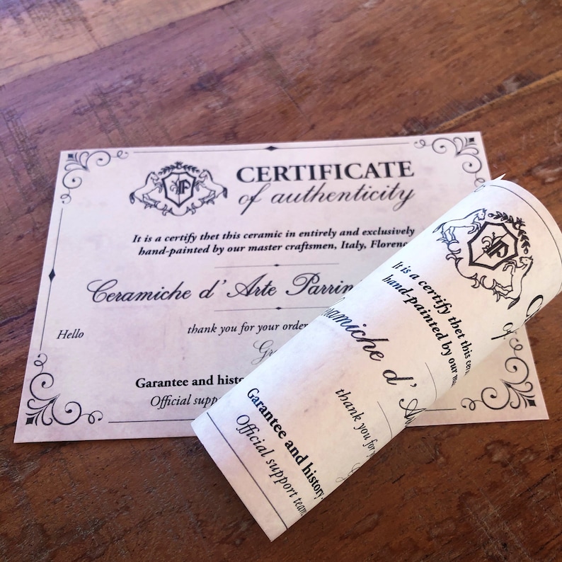 May include: A certificate of authenticity for a ceramic piece. The certificate is printed on parchment paper and features a crest with the words "Ceramiche d'Arte Parrini" and "Certificate of Authenticity".