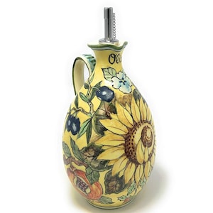 May include: Yellow ceramic olive oil bottle with a sunflower, olives, and other floral designs. The bottle has a spout with a silver stopper and a chain.
