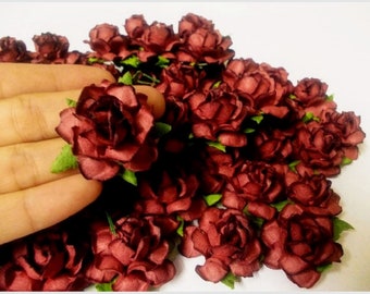 Op de afbeelding: Een grote bos kleine, bordeauxrode papieren rozen. De rozen zijn in een tros gerangschikt en hebben een licht gekrulde uitstraling.