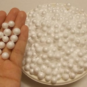 Puede incluir: Una mano sosteniendo un puñado de pequeñas bolitas de poliestireno blancas. Un tazón lleno de bolitas de poliestireno blancas está en el fondo.