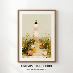 Puede incluir: Una lámina de arte enmarcada que muestra un faro con rayas rosas y blancas, rodeado por un campo de flores silvestres amarillas y naranjas y calabazas. El texto GRUMPY GAL GOODS ALL THINGS PRINTABLE aparece en negro bajo el marco.