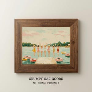 Op de afbeelding: Een ingelijste kunstdruk met een schilderij van zeven personen in kleurrijke badkleding die vanaf een houten steiger in een meer met zwembanden springen. De tekst GRUMPY GAL GOODS ALL THINGS PRINTABLE staat onder de houten lijst.
