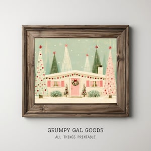 May include: A framed print featuring a light-colored house with pink shutters and a pink door, decorated with a wreath. The scene includes several stylized Christmas trees in shades of pink, white, and green against a light blue snowy background.