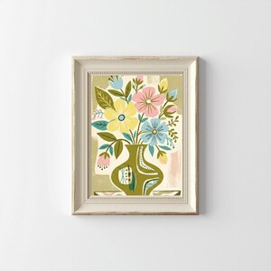 Peut inclure: Une impression d'art encadr&eacute;e repr&eacute;sentant un arrangement floral stylis&eacute; dans un vase vert. Les fleurs sont jaunes, roses et bleues, avec des feuilles vertes. Le vase pr&eacute;sente des motifs d&eacute;coratifs. Le cadre est blanc cass&eacute;.