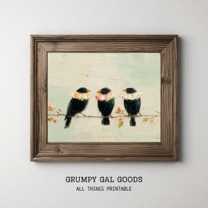 May include: A framed oil painting print featuring three black birds with ruffled white and pink collars perched on a thin branch against a pale blue textured background. The text GRUMPY GAL GOODS ALL THINGS PRINTABLE appears below the frame.