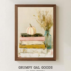 May include: A framed wall art print featuring an oil painting of a stack of four books in dark green, pink, white, and mustard yellow. A small white pumpkin sits on top of the books next to a light blue glass vase filled with dried wheat stalks.