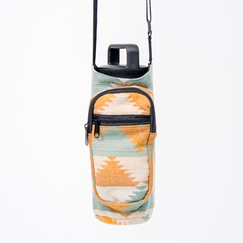 May include: A water bottle carrier with a black handle and strap. The carrier features a geometric pattern in green, orange, and cream. It has a small zipped pocket on the front.