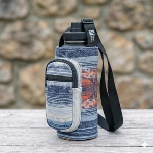 May include: A black water bottle with a blue and orange patterned sleeve and a small zippered pouch. The sleeve has a black strap for carrying. The text "feel good" is printed on the strap.