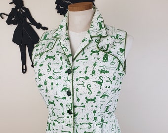 May include: A white sleeveless dress with a green pattern of keys and other symbols. The dress has a button-up front and a collared neckline.